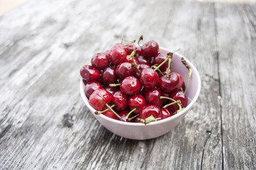 Bowl of cherries on a worn wooden background