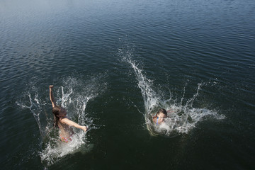 Obraz premium Twin girls jumping off dock.