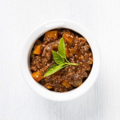 Bolognese sauce. In a white plate. Basil. The background is white. Italian food. Copy space. Top view. A square shot.