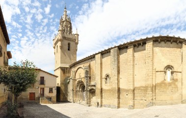 Fototapeta na wymiar The Holy Mary square and church (Iglesia de Santa Maria) with its bell tower, together with typical stone made Spanish houses in Uncastillo, a small rural town in the Aragon region, in Spain