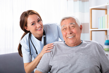 Senior Man Sitting On Wheelchair With Female Nurse