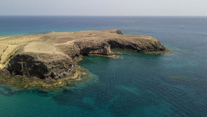 Obraz premium Vista aerea delle coste frastagliate e delle spiagge di Lanzarote, Spagna, Canarie. Strade e sentieri sterrati. Bagnanti in spiaggia e nell’Oceano Atlantico. Papagayo