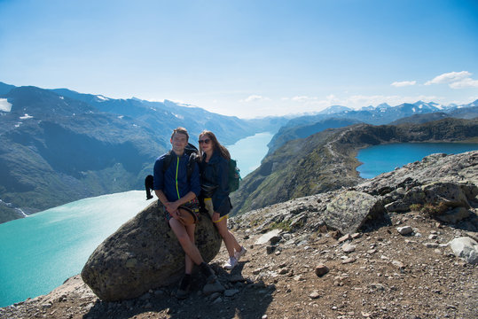 hikers resting on stone on Besseggen ridge over Gjende lake in Jotunheimen National Park, Norway
