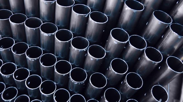 Metal profile pipe of round section in packs at the warehouse of metal products. Close-up of metal pipe. Warehouse for finished products of metal pipes of circular cross-section at the factory.