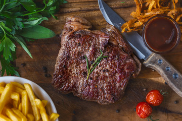 Gegrilltes Rinder Steak mit Pommes Frites auf dem Oktoberfest Biergarten auf einem Holzbrett...