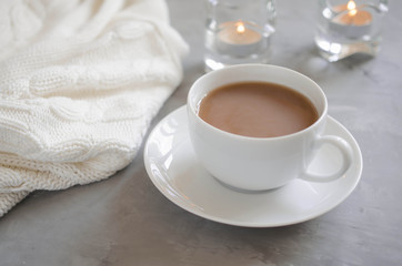 Cup of cocoa on a table, candles and knited blanket.