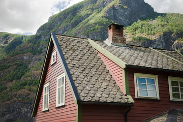 low angle view of beautiful wooden house in Flam village and majestic mountains, Aurlandsfjord (Aurlandsfjorden), Norway