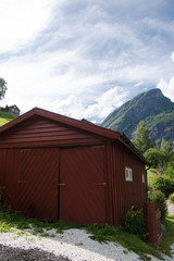 Fototapeta na wymiar brown wooden barn and beautiful mountains behind, Aurlandsfjord, Flam (Aurlandsfjorden), Norway