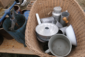 metal objects like bowls and can on flea market in a basket.