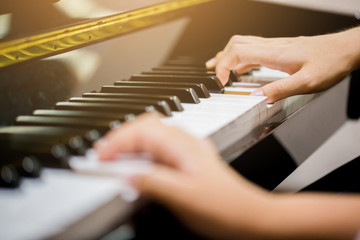 Fototapeta premium Selective focus to fingers of woman teaching boy to play the piano.