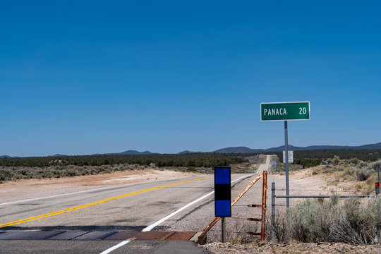 Road sign for Panaca Nevada 20 miles away. Cattle guard on the empty rolling highway