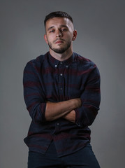 Obraz premium Man looking at camera. Portrait handsome in checkered shirt cross hands on breast. Copy space grey background