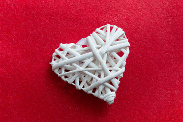 Cuore bianco di vimini intrecciato su sfondo rosso 