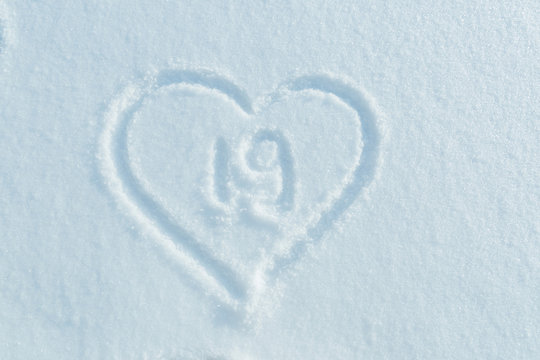 A figure of Nineteen written in the snow in the painted heart. Snow texture.