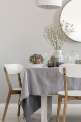 White chairs and laid table in an elegant and pastel dining room interior. Real photo