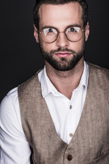 portrait of elegant bearded man posing in eyeglasses, isolated on grey