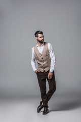 handsome bearded man posing in elegant stylish waistcoat on grey