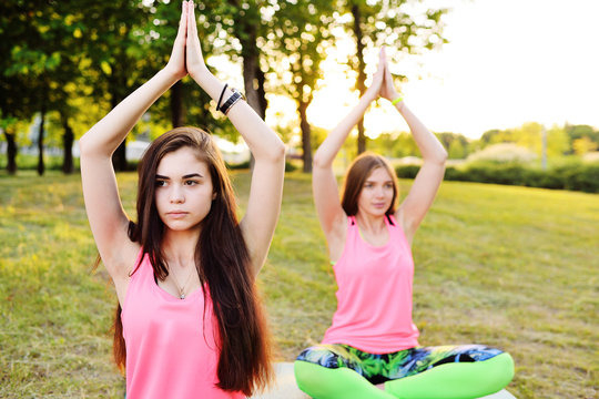 A group of young slender, beautiful girls doing yoga or fitness on fresh grass 