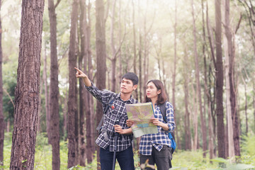 Asian young couples traveler with backpack looking map at sunny forest