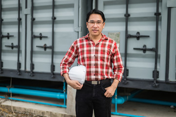 portrait of engineer holding helmet and standing at construction site area. he smile after construction complete.