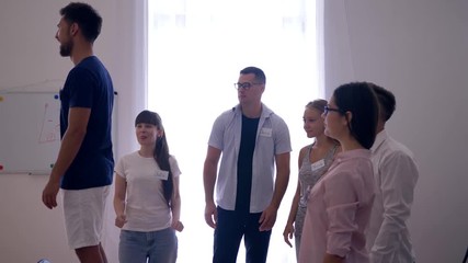 trust in team, man on a chair falls down on back and colleagues catch and applaud him on group therapy