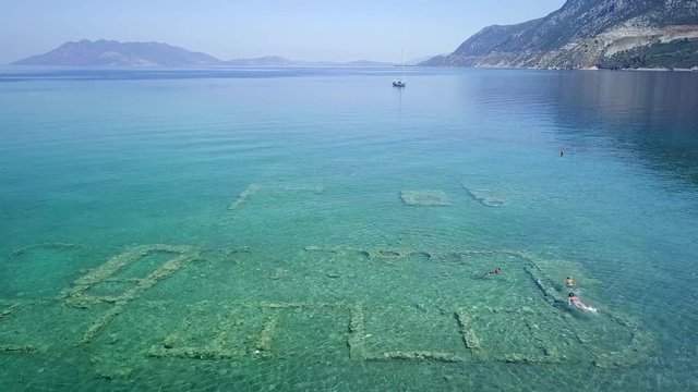 Aerial drone bird's eye view photo of tourists snorkeling above old Sunken City of Epidauros, Greece