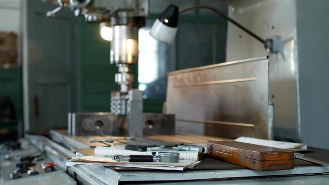 A private workshop for working with metal parts, in the background a drilling machine drills a hole in the pulley, on the table lie measuring tools, production, small business