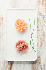 Fish tartare, salmon and tuna on a white rectangular dish over a wooden table,   with balsamic oil and  and chives.Natural light ,top view over a white board.