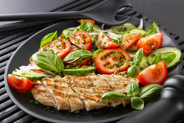 Vegetable salad and grilled chicken on a black background. Healthy food. Diet.