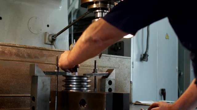 The male specialist measures the size of the tolerance device and the value in the metal pulley for manufacturing, close-up, micrometer