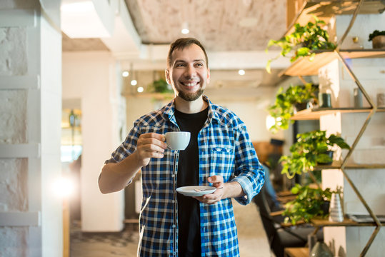 Bearded hipster man in checkered shirt drinks coffee