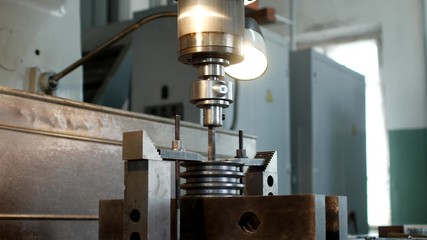 Drilling a hole with a drilling machine in a metal workpiece pulley, close-up, industry, manufacturing pulley