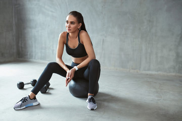 Obraz na płótnie Canvas Sports Woman In Fashion Sportswear Sitting On Fitness Ball
