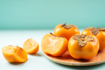 Half and sliced persimmon fruit on wooden plate and color background, healthy fruit