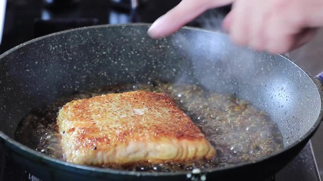 cooking salmon in a pan on oven
