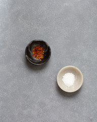 Black and white bowls with salt and chili flakes