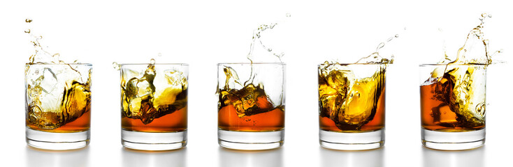 Scotch glasses with whiskey splashing from them - obrazy, fototapety, plakaty