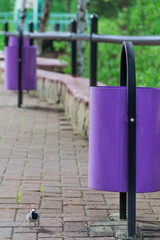 Violet, iron street urns on the background of a stone pavement. Ecology and cleanliness.