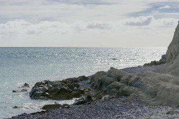 Small waves hit the rocks at the beach in a sunny day.