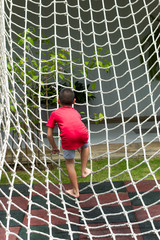 Boy climbing a rope net on the playground.