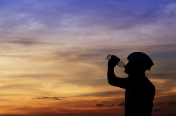 Close-up silhouette of the man drinking water with beautiful at sunset