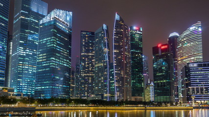 A view of Singapore business district skyscrapers in the night time with water reflections timelapse hyperlapse