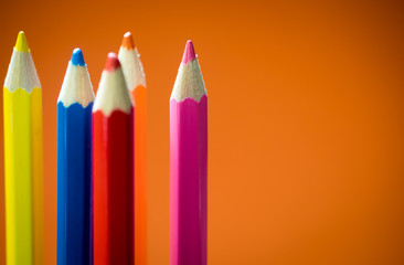 Set of multicoloured  pencil or crayon on orange background.Selective focus