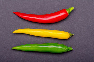 green red yellow  chili on dark background