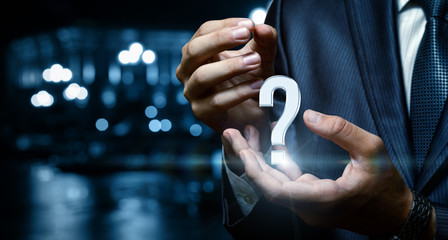 Question mark in the hand of businessman over city background.