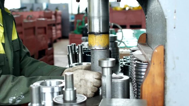The worker assembles the pressing of the bearing into a metal clip on the machine, assembles the finished unit, close-up, press, pucker