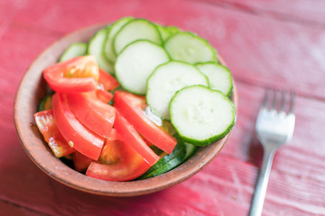 Salad of fresh tomatoes and cucumbers. Sliced tomatoes and cucumbers in a deep plate.