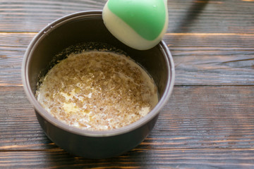 Oatmeal porridge cooked on milk in a saucepan on a dark wooden background.