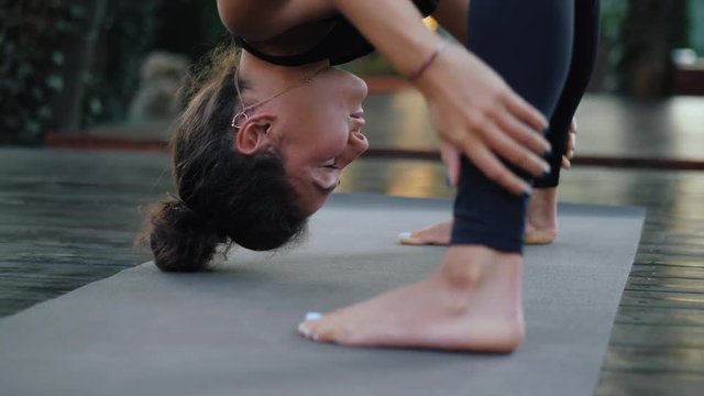 Professional gymnast fitness instructor doing Uttanasana standing barefoot on yoga mat. Flexible woman stretching forward, head inclination to legs. healthy lifestyle concept.