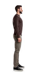 A bearded man in casual clothes stands still with arms hanging straight on his sides in a side view. © gearstd